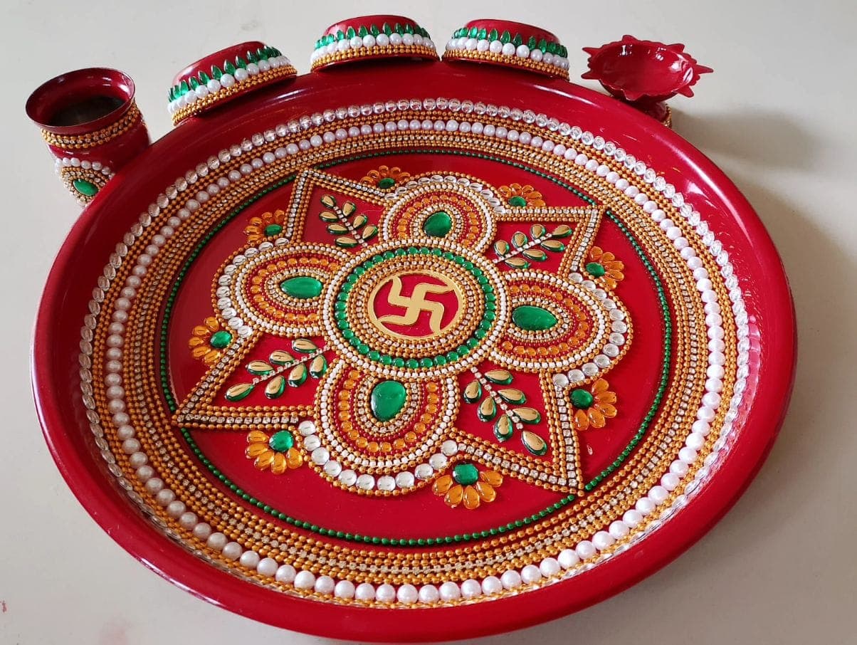 Traditional red swastik pooja thali with floral design, emerald stones and kumkum containers